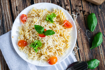 Macaroni with cheese and vegetables. On a wooden background