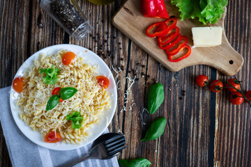 Macaroni with cheese and vegetables. On a wooden background
