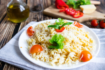 Macaroni with cheese and vegetables. On a wooden background