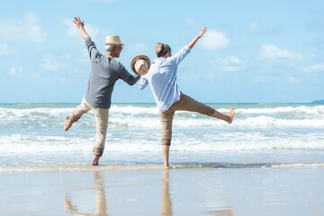 Asian Lifestyle senior couple walking chill and jumping on the beach happy in love romantic and relax time after retirement.  People tourism elderly family travel leisure and activity after retirement - obrazy, fototapety, plakaty