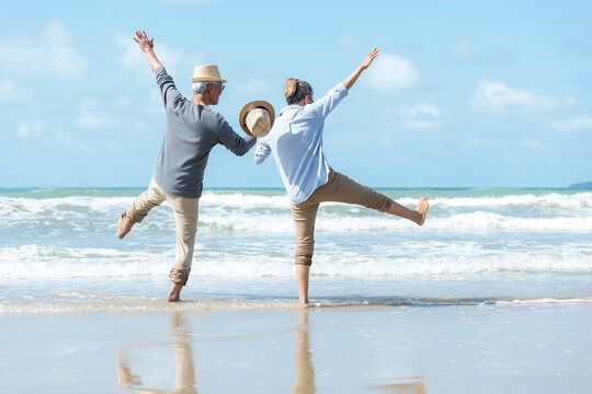 Asian Lifestyle Senior Couple Walking Chill And Jumping On The Beach Happy In Love Romantic And Relax Time After Retirement.  People Tourism Elderly Family Travel Leisure And Activity After Retirement