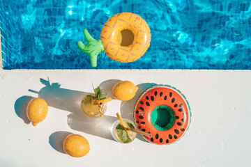 Drink at poolside. Cocktail at swimming pool with inflatable rings. Vacation, beach, summer travel concept