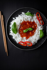 Rice with sweet and sour sauce. Dinner. On a black background
