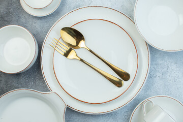 Cutlery set on white plates on half dark light gray background with distressed surface