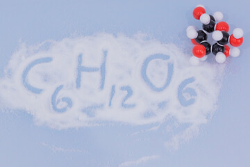 Isolated glucose molecule made by molecular model with glucose formula written on white sugar....