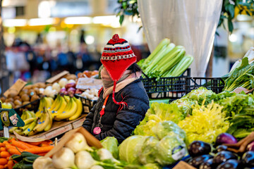 Verkäuferin an einem Obststand mit Jacke, Schal und Mütze schützend vor der Kälte