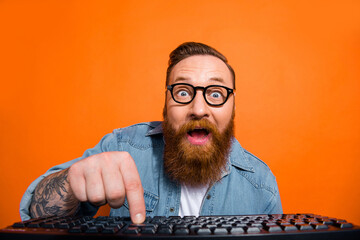 Closeup photo of excited funny businessman try launch his first ecommerce product wear glasses click keyboard isolated on orange color background
