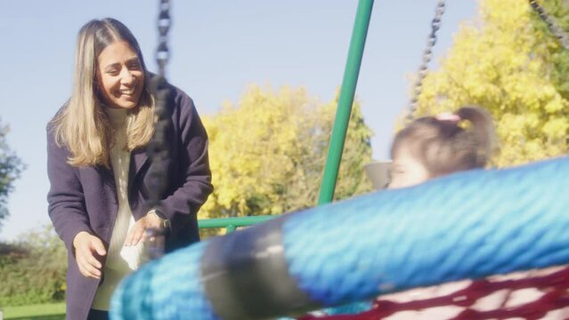 MS SLO MO Mother swinging daughter (2-3) with Down syndrome on swing