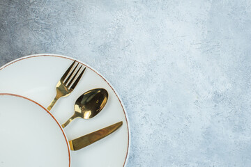 Elegant cutlery set between empty white soup plates on half dark light gray background with distressed surface with free space in half shot view
