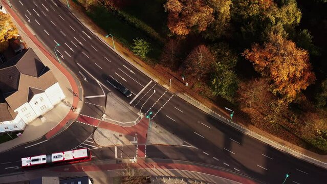 Drone at a standstill with a view of a crossroad with pedestrians and stationary and moving cars in Neubrandenburg.