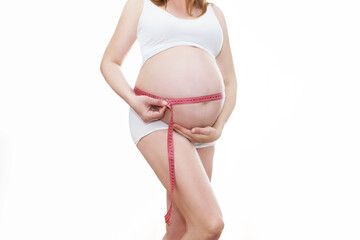 Młoda piękna ciężarna dziewczyna mierzy jej brzuch taśmą w domu. Koncepcja zdrowej ciąży. ...