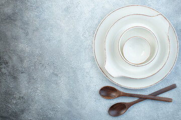Elegant empty white set for dinner and wooden spoons on isolated gray background with free space