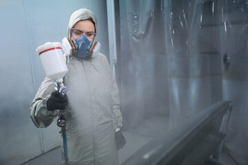 Automobile repairwoman servicing car in painting booth