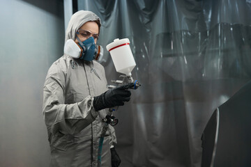 Photo of woman car technician holding spray gun indoors