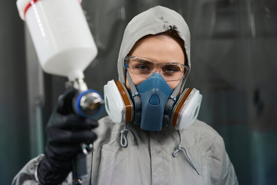 Pretty woman worker demonstrating aerograph at camera