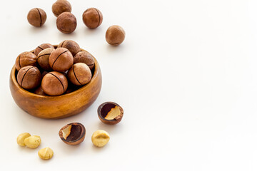 Wooden bowl of raw macadamia nuts in shell. Healthy protein snack background