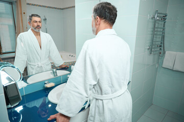 Obraz premium Man morning routine near the mirror in apartment