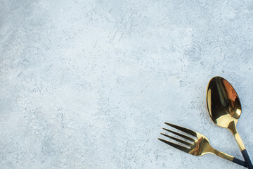 Half shot of elegant cutlery set on gray background with distressed surface with free space