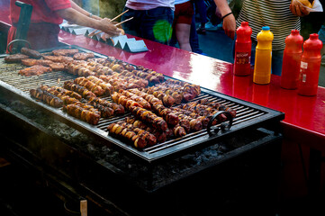 View over a grill on which skewers are prepared over charcoal on a street festival.