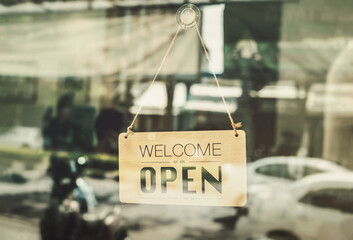 Open sign broad hanging on wood door front of cafe. Welcome. Open. open sign board on glass door in modern cafe coffee shop ready to service, cafe restaurant, retail store, small business owner.