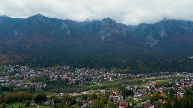 Drone footage of cityscape with Suburbs houses and trees with foggy mountains under cloudy sky