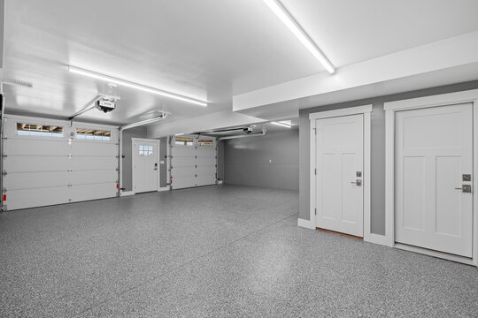 Interior view of an empty garage with a metallic surface floor and lighting