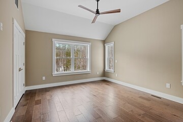 Empty room with wooden floors, a ceiling fan and white brown walls