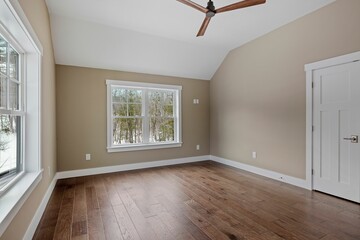 Modern living room interior showcasing hardwood flooring, a ceiling fan and large windows