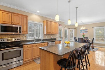 Contemporary kitchen features modern hardwood flooring, glossy granite counter tops