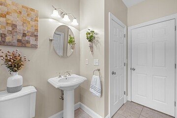 White bathroom with a mirror, sink, toilet and door