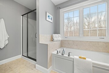 Clean bathroom with a shower, bathtub and large window