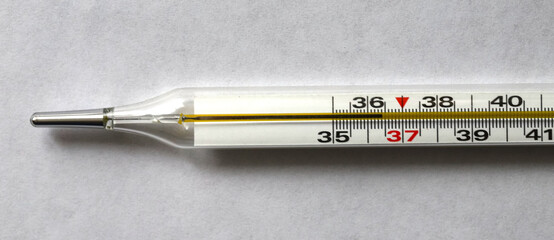 Medical mercury thermometer, on the background of a medical mask. Glass thermometer for measuring...