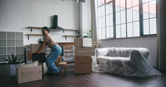 Hispanic woman carrying cardboard boxes dances with smile