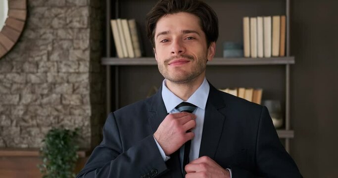 Portrait of handsome businessman getting ready by adjusting necktie in the office