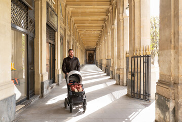 Obraz premium Father pushing his sleeping daughter in a stroller in the galleries of the Palais-Royal in Paris.