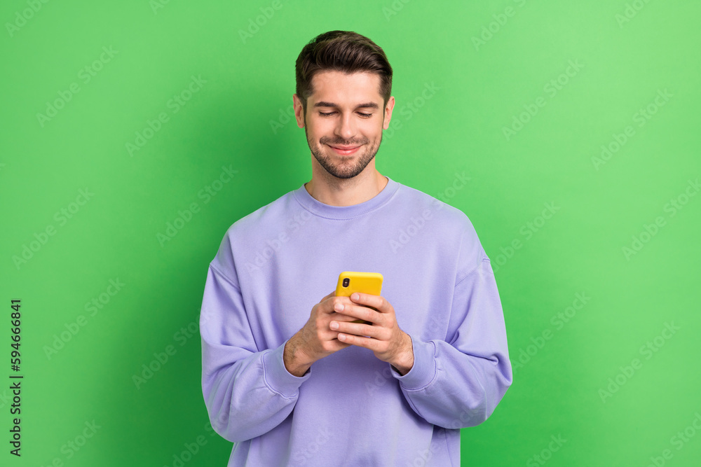Poster portrait of positive blogger man hold use telephone chatting communicate isolated on green color bac
