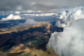 Fototapeta premium Aerial view at high altitude of earth covered with puffy cumulus clouds forming before rainstorm