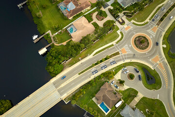 Aerial view of american suburban area with rural road roundabout intersection with moving cars traffic. Circular transportation crossroads in Florida