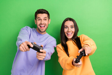 Photo of two overjoyed partners hands hold controller play video games isolated on green color...