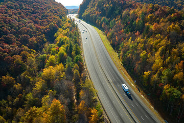 Obraz premium Aerial view of I-40 freeway in North Carolina leading to Asheville through Appalachian mountains in golden fall with fast moving trucks and cars. Interstate transportation concept