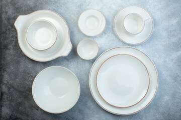 White dinnerware set including many empty plates on half dark light gray background with distressed surface