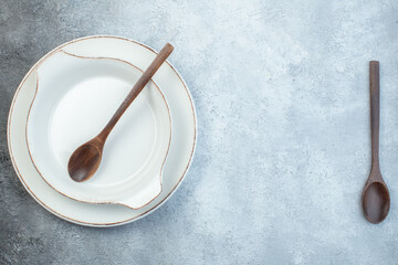 Wooden spoons and empty soup plates on half dark light gray background with distressed surface with free space