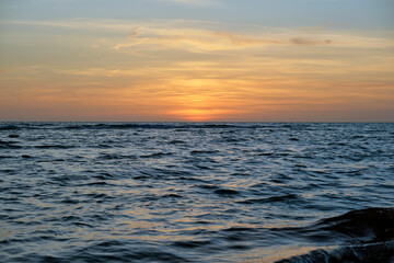 Dramatic red ocean waves at sunset with soft evening sea dark water