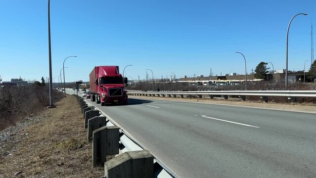 Semi-truck passes a camera on a busy highway exiting Halifax, Canada. big semi trailer with cargo trailer moving on road with cars, low view angle. 