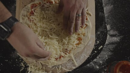 Close-up slow-motion view of a person sprinkling cheese on a homemade pizza in a kitchen