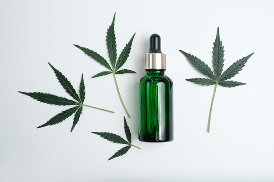 Jar of hemp sbd and thc oil on a white background with cannabis leaves. Marijuana resin treatment concept