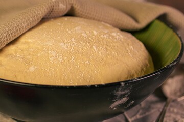 Closeup of a bowl filled with dough covered by a towel