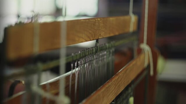 Rearview of traditional hand weaving machine as worker pulls loom