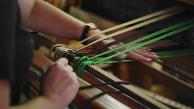 Woman ties knots and smoothes out yarn preparing hand weaving on loom