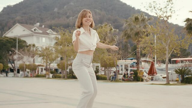 Young woman is circling on roller skates and smiling carelessly